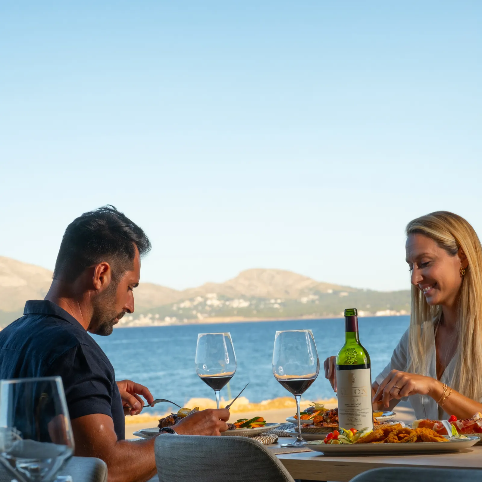 Comer frente al mar en el Puerto de Pollensa Pareja comiendo frente al mar en la terraza de Can Josep, Puerto de Pollensa